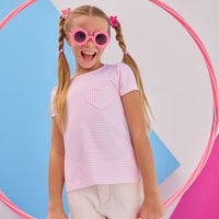 Model can be seen wearing Girls/Tween short sleeve knit top in a light pink and white stripe. Top also features a faux heart pocket to elevate the tee. Paired back perfectly with ivory denim shorts to complete the look. 