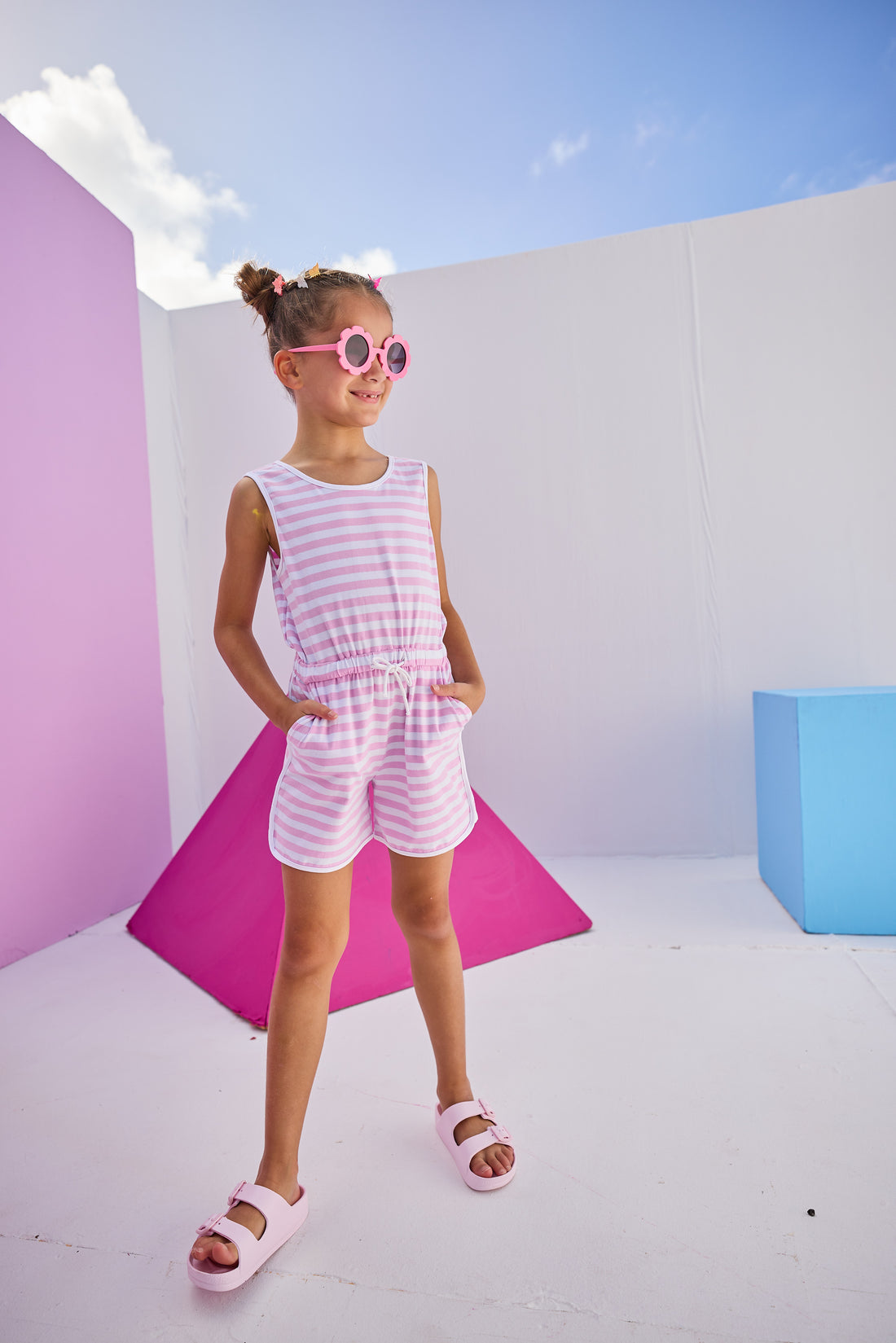 Girls/Tween model can be seen wearing  knit romper in light purple/white stripe. Romper features a keyhole button closure at back , an elastic waistband, and pockets.