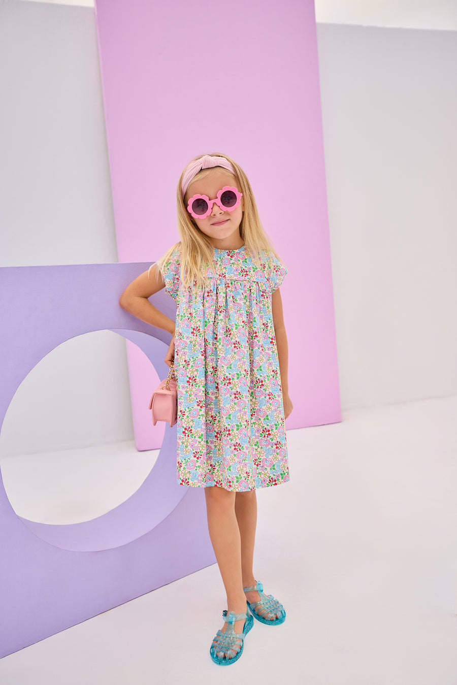 Girls/tween woven dress in a pale yellow/pink/blue/green floral pattern. Dress is made of a lightweight woven material, is lined, and has a 3 button closure along back for a secured but relaxed fit. 