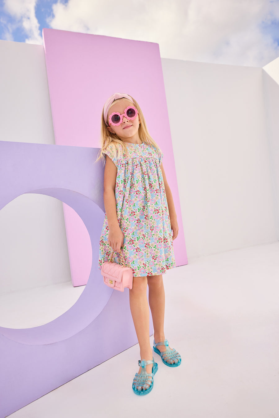 Girls/tween woven dress in a pale yellow/pink/blue/green floral pattern. Dress is made of a lightweight woven material, is lined, and has a 3 button closure along back for a secured but relaxed fit. 