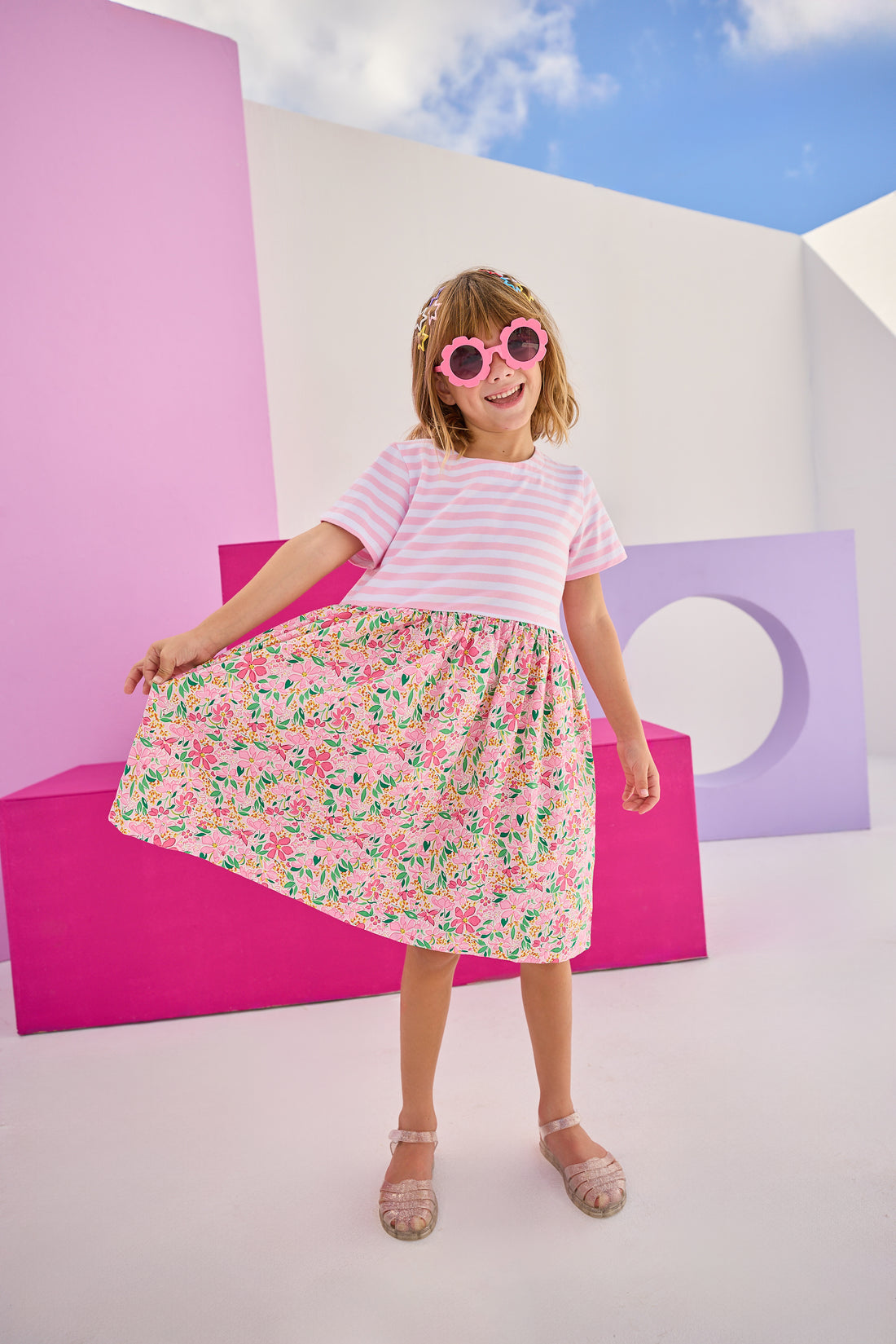 Model can be seen wearing a half knit half woven dress with knit pink/white stripe top half and a woven skirt with pink/yellow floral print. There is also a three button closure along back for a relaxed but secure fit.