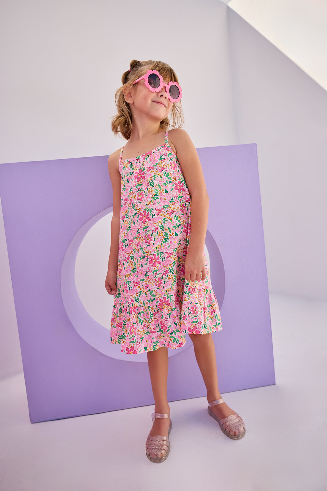 Model can be seen in woven dress with thin straps in a hot pink/yellow/white floral pattern. Dress is made up of a lightweight woven material for a perfect spring/summer dress.