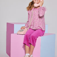 Tween girls square neck, three quarter sleeves with angel sleeve ruffles  in a hot pink floral print paired with cropped velour pants in magenta.