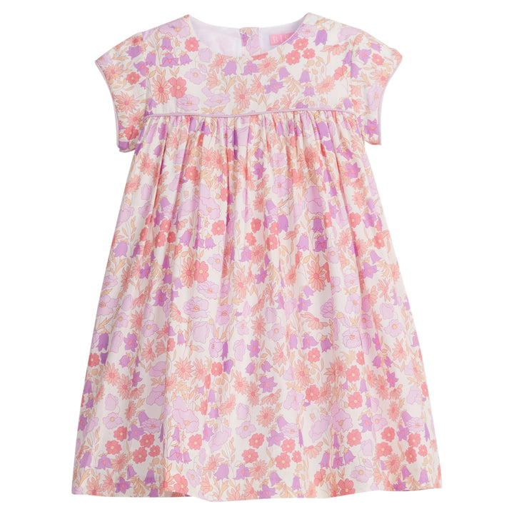 Girls/Tween short sleeve woven dress in a light purple/salmon/pink floral arrangement. Dress also features button closure at back and a light purple trim across the bust and continues at trim of sleeves for a nice extra detail. 