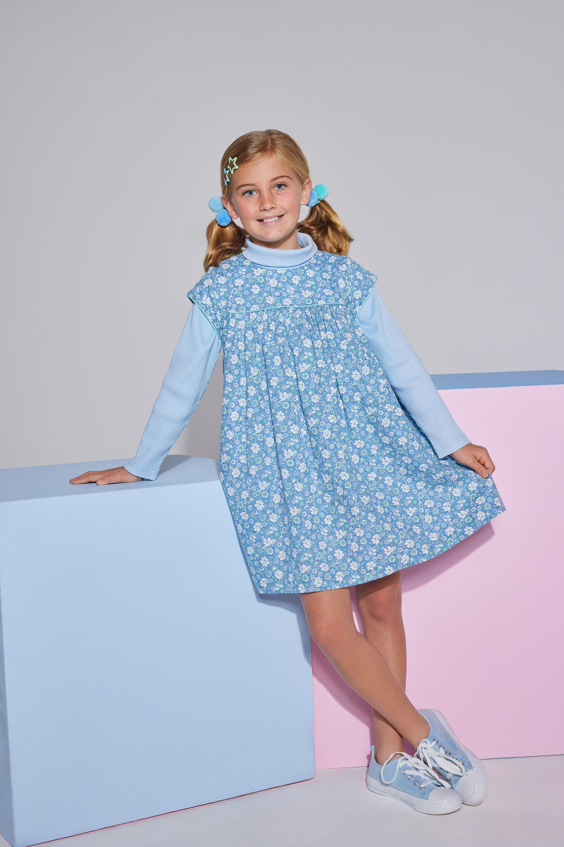 Girls short sleeve dress in blue/green/white floral print with aqua trim detailing that has button closures along back paired with a light blue turtleneck underneath.