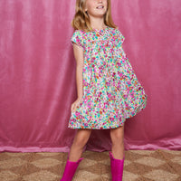 Girls short sleeve dress in magenta/pink/orange/green floral print with light pink trim detail and button closures along back.