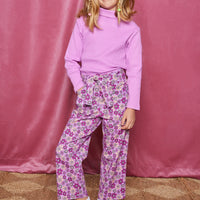 Tween woven pant with pockets  in a purple/magenta/pink floral pattern that comes with a belt in the matching print and button/zipper closure in front of pants paired back with a magenta ribbed turtleneck.