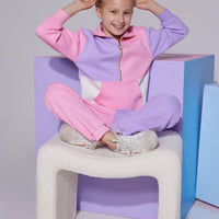 Tween color block quarter zip pullover that features a gold zipper detail and large front pocket in purple/pink/white color block that pairs back with the matching jogger pant that has one pant leg in pink and one leg in lilac to complete the set.