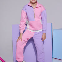 Tween knit jogger pant with elastic waistband that features one pant leg in a light pink and one leg in lilac which pairs back with the matching quarter zip pullover with a gold zipper detail, pocket in the front, and pink/white/purple color block print.