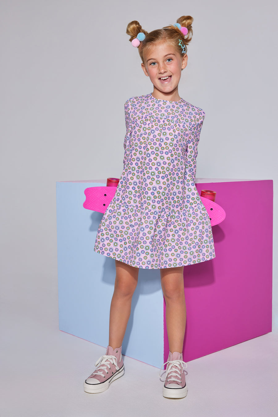 Girls/tween woven dress in light pink/purple/yellow floral print featuring long sleeves and button closures along back.