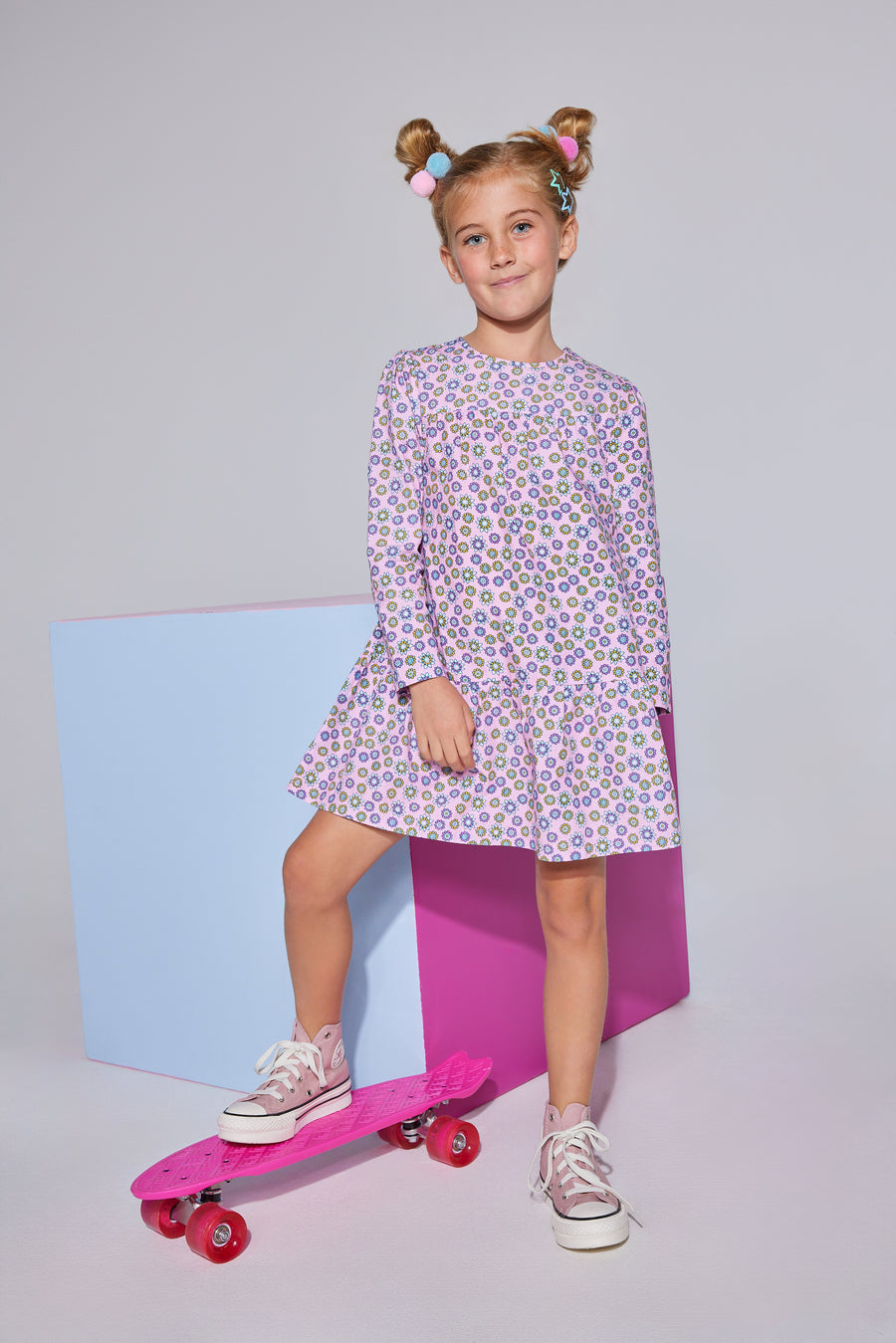 Girls/tween woven dress in light pink/purple/yellow floral print featuring long sleeves and button closures along back.