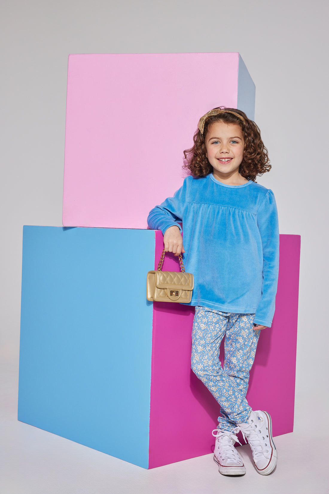 Girl/tween French blue velour long sleeve top featuring gathering detail along bust and button closures along back which can be seen paired with knit leggings in a blue floral print to complete the look.