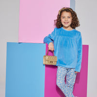 Girl/tween French blue velour long sleeve top featuring gathering detail along bust and button closures along back which can be seen paired with knit leggings in a blue floral print to complete the look.