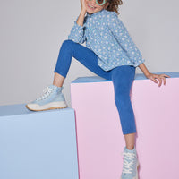 Girls/Tween woven long sleeve top in a blue/green floral print which features a ruffled neckline, elastic cuffs at end of sleeves, and an gathering detail at bust for a relaxed fit. Top pairs back perfectly with dusty blue corduroy pants.