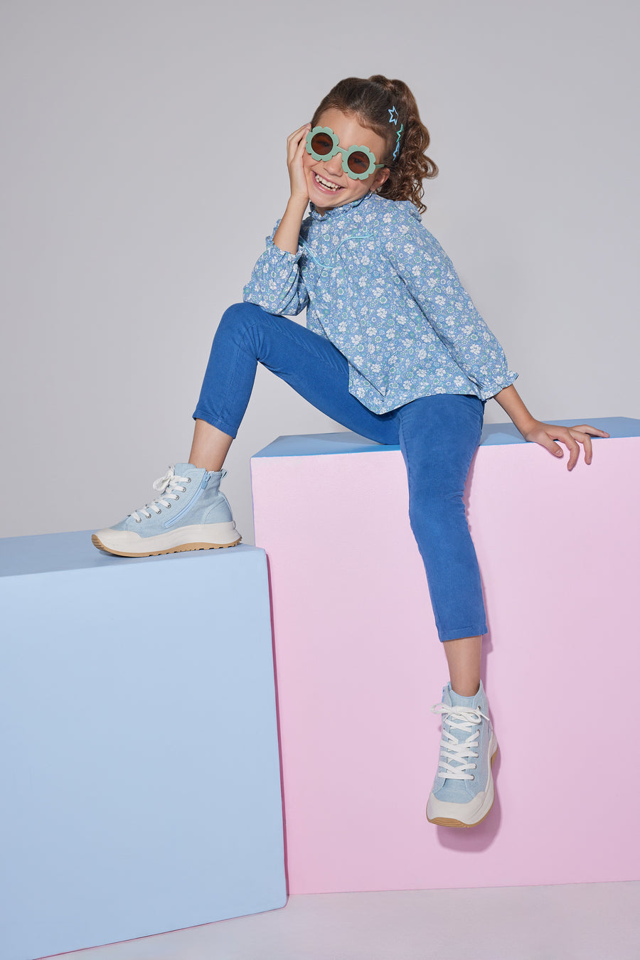 Girls/Tween woven long sleeve top in a blue/green floral print which features a ruffled neckline, elastic cuffs at end of sleeves, and an gathering detail at bust for a relaxed fit. Top pairs back perfectly with dusty blue corduroy pants.