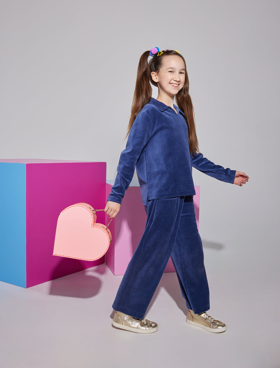 Girl/Tween cropped velour pants in a navy velour color. Pants feature an elastic waistband and pockets in the front of the pants. Material is also made of a very soft/warm velour. Model can be seen pairing pants with the matching polo pullover in the same navy velour to complete the look.