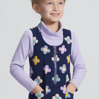 Girls/Tween jumper in a lightweight corduroy material. Jumper has a zipper down the front, pockets, and can be seen in a purple/blue/yellow floral arrangement on a navy background. Perfect as a layering piece, as seen model is wearing a ribbed turtleneck in lilac which pulls back in nicely with the jumper.