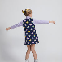 Girls/Tween jumper in a lightweight corduroy material. Jumper has a zipper down the front, pockets, and can be seen in a purple/blue/yellow floral arrangement on a navy background. Perfect as a layering piece, as seen model is wearing a ribbed turtleneck in lilac which pulls back in nicely with the jumper.