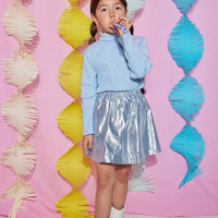 Tween skort with built in shorts and an elastic waistband in a icicle blue metallic color paired back with an ice blue ribbed turtleneck to complete the look.