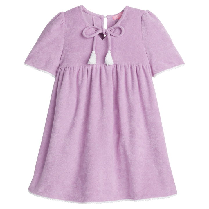 Girls/Tween lilac terry cloth dress that features a slight v-neckline, light pink pom pom detail at sleeves, and tie tassels at top of neckline. There is also a button closure at back for a relaxed but secure fit. 