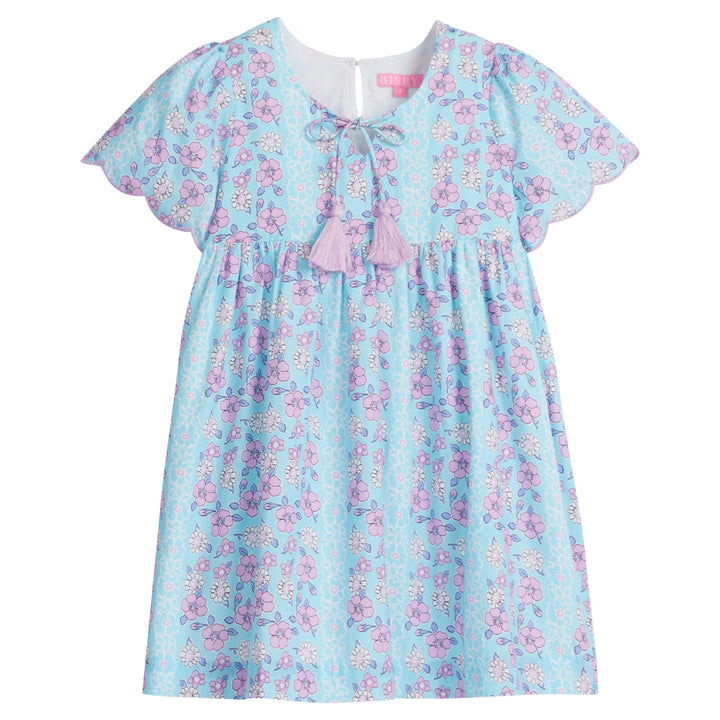 Girls/Tween woven dress in aqua/purple/white floral pattern. Dress features a slight v-neckline, tie tassel at neckline with lilac tassels, and scallops at end of sleeves to complete the look. There is also a button closure at back for a relaxed but secure fit. 