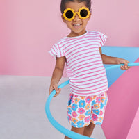 Model wearing BISBY Rosie Short Set in flower market print of pink, blue, and orange flowers, and a top with pink and white stripes and flutter sleeves. 