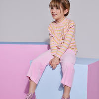 Girl/Tween cropped velour pants in the light pink velour shade. Pants feature a soft velour material, with pockets in the front, and an elastic waistband for a comfy fit. Model can be seen wearing a knit top with angel sleeves in a pastel stripe pattern to complete the look. 